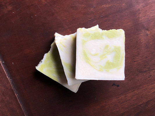 Three green and white rustic bars of soap on a brown wood background 