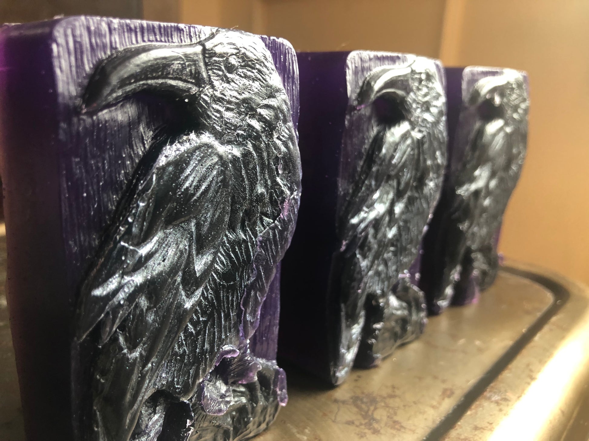 three bars of soap with ravens birds on a stool. bars are purple witih black raven bird in profile