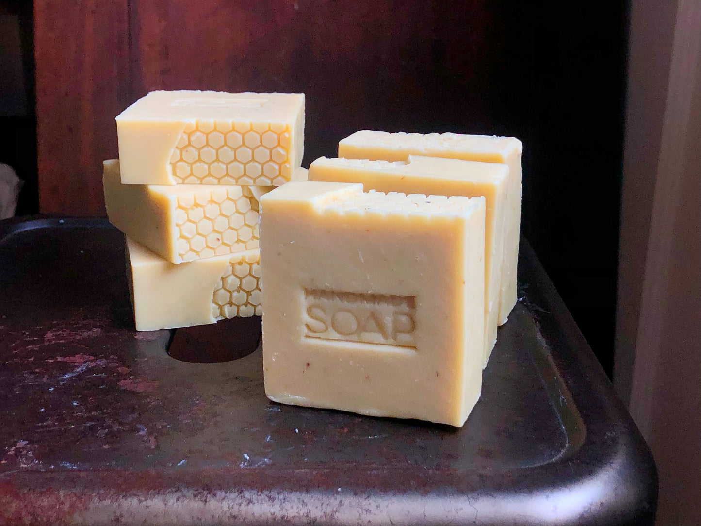 six bars of beige soap with honeycomb pattern top on a metal stool