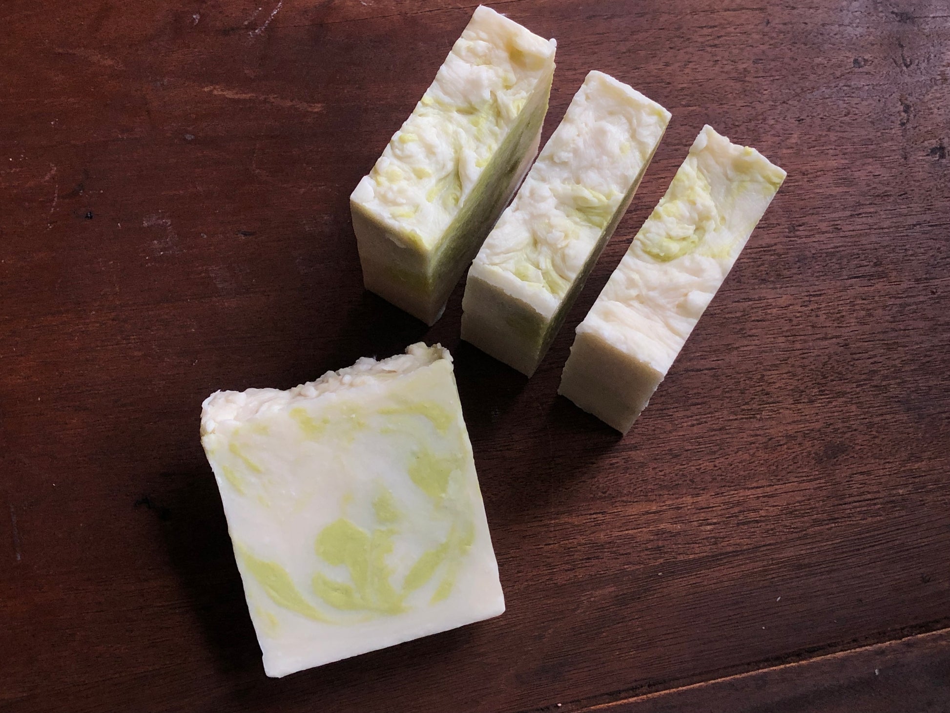 Three green and white rustic bars of soap on a brown wood background 